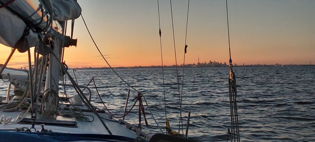 Sailboat silhouetted against a glowing sunset on open water, capturing a peaceful evening under sail